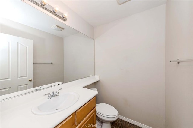 half bathroom featuring visible vents, vanity, toilet, and baseboards