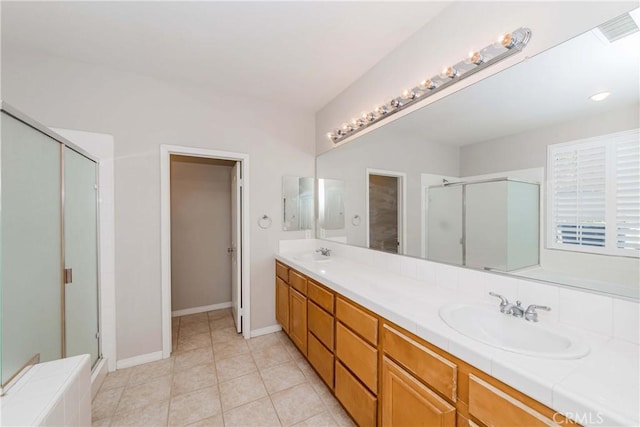 bathroom featuring tile patterned floors, a sink, a shower stall, and double vanity