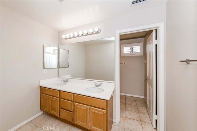 bathroom featuring visible vents, a sink, baseboards, and double vanity