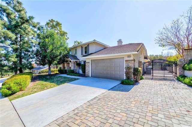 traditional-style home with concrete driveway, stone siding, a chimney, an attached garage, and a gate