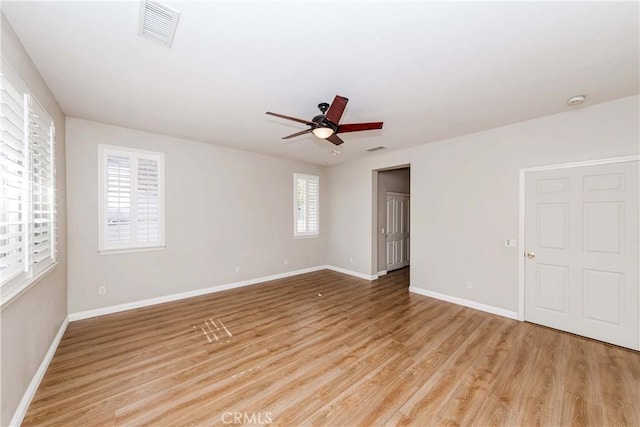 empty room featuring light wood-style flooring, a ceiling fan, visible vents, and baseboards