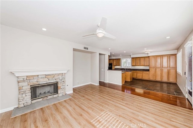 unfurnished living room featuring baseboards, dark wood-style flooring, and a stone fireplace