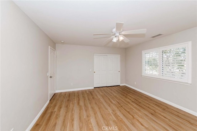 unfurnished room with visible vents, ceiling fan, light wood finished floors, and baseboards