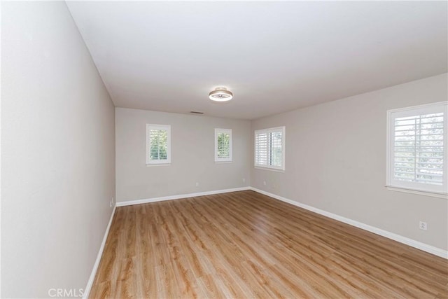 unfurnished room with light wood-style floors, visible vents, and baseboards