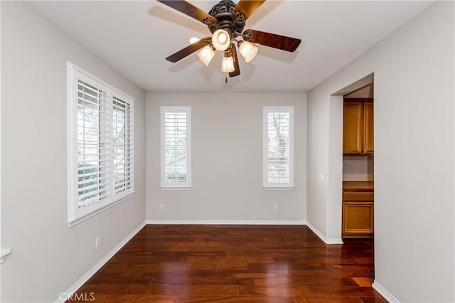 empty room featuring a ceiling fan, baseboards, and wood finished floors