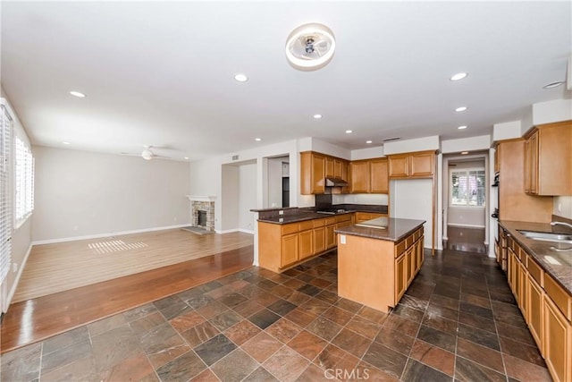 kitchen with recessed lighting, dark wood-style flooring, a fireplace, baseboards, and open floor plan