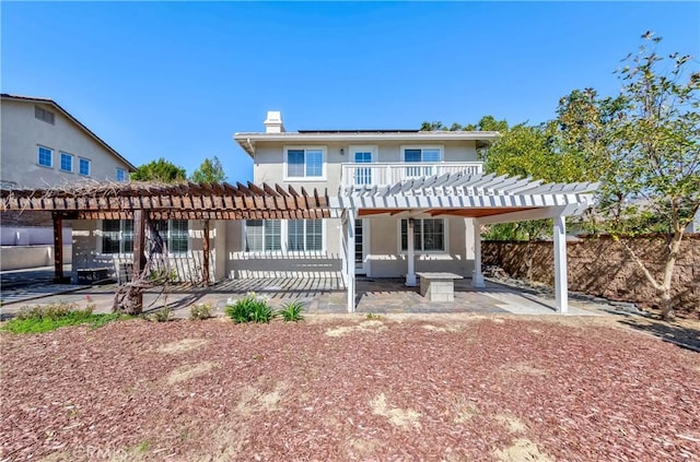 rear view of house with roof mounted solar panels, a patio area, a chimney, and a pergola