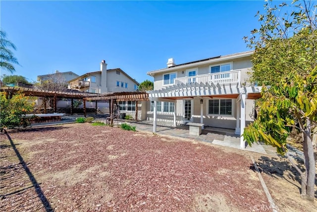 back of property with a patio area, solar panels, a pergola, and stucco siding