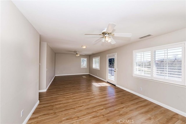 unfurnished room with a ceiling fan, light wood-style flooring, visible vents, and baseboards