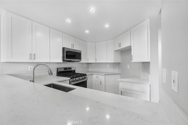 kitchen with a sink, recessed lighting, appliances with stainless steel finishes, and light stone counters