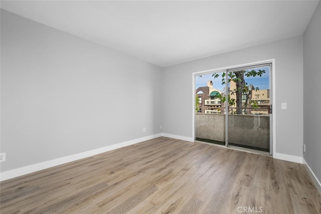 spare room featuring baseboards and wood finished floors