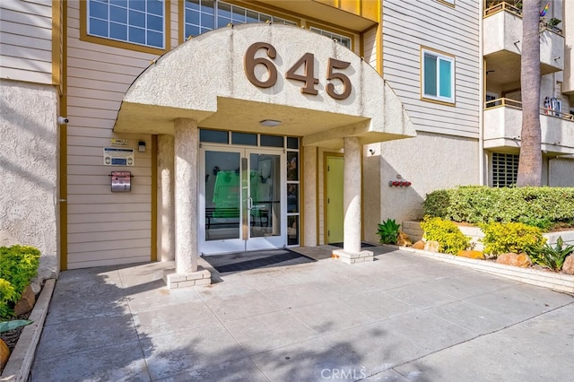 entrance to property featuring french doors and stucco siding