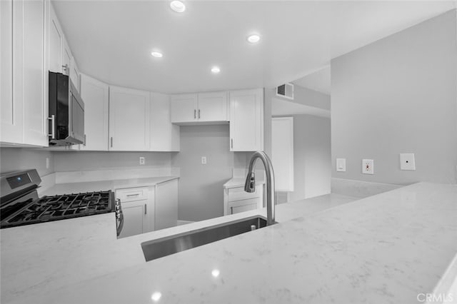 kitchen with stainless steel appliances, a sink, visible vents, and light stone countertops