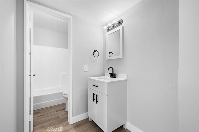 bathroom with baseboards, vanity, toilet, and wood finished floors