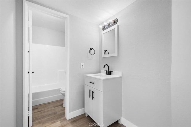 full bathroom with toilet, wood finished floors, vanity, and baseboards