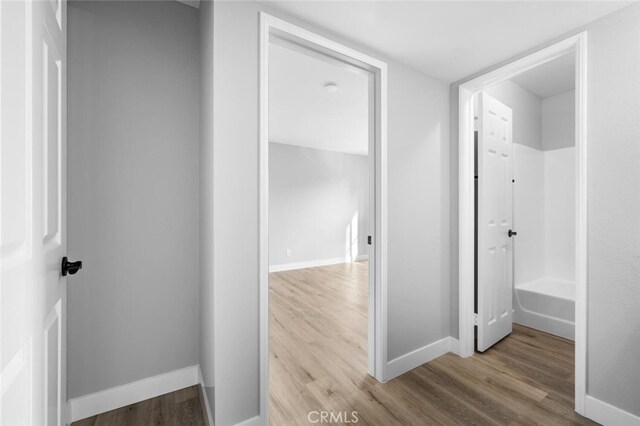 corridor featuring baseboards and wood finished floors