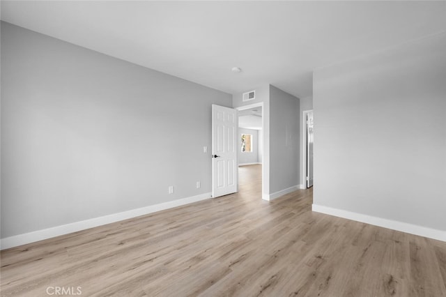 empty room featuring light wood-style flooring, visible vents, and baseboards