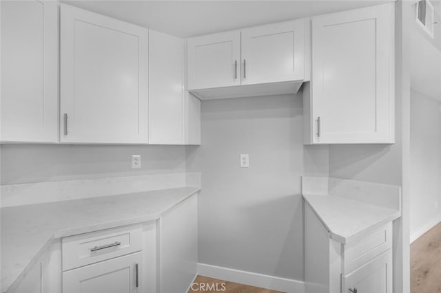 kitchen with white cabinetry, visible vents, wood finished floors, light countertops, and baseboards
