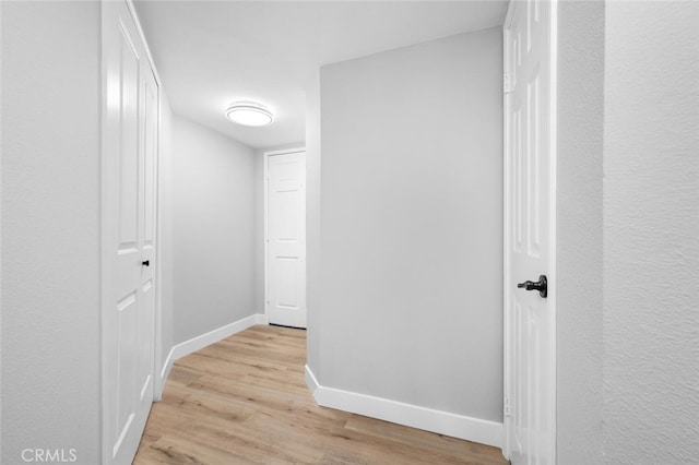 hall featuring light wood-type flooring and baseboards
