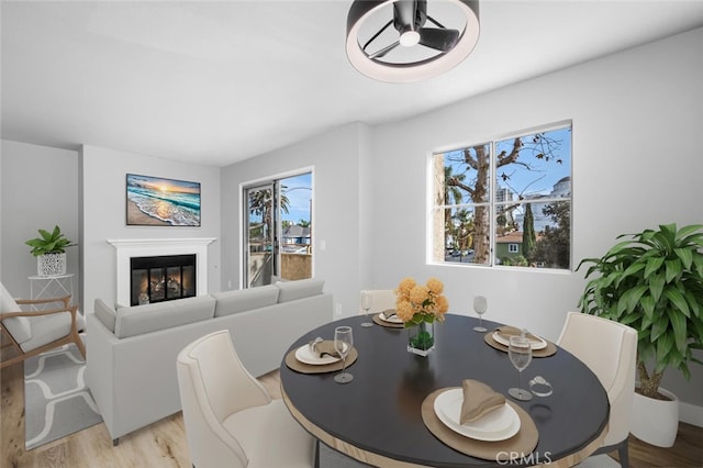 dining room with light wood-type flooring and a glass covered fireplace