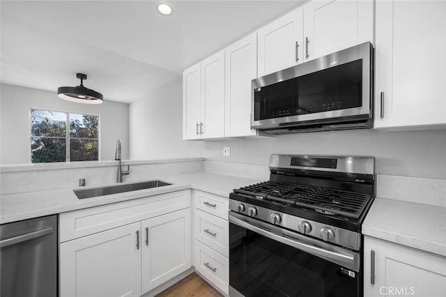 kitchen with appliances with stainless steel finishes, light countertops, white cabinets, and a sink