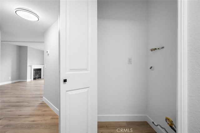 corridor featuring light wood finished floors and baseboards