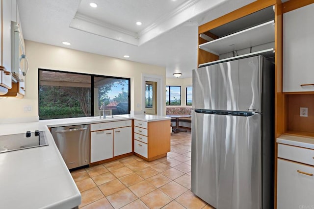 kitchen featuring a raised ceiling, light countertops, stainless steel appliances, a sink, and light tile patterned flooring