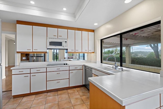 kitchen with black electric stovetop, white microwave, a sink, light countertops, and stainless steel dishwasher