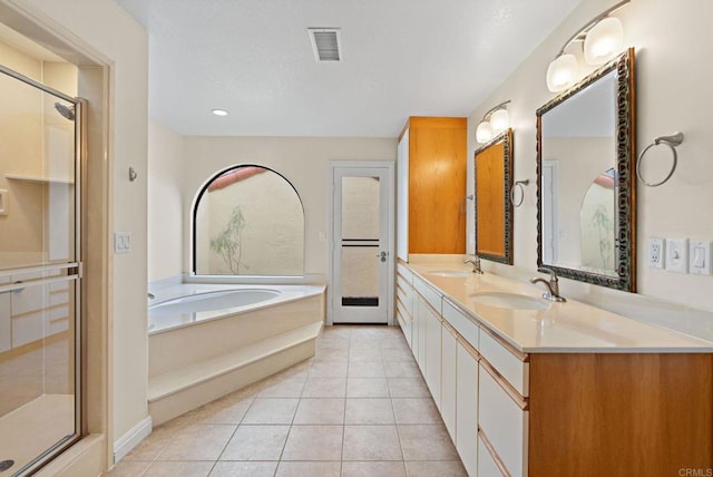 bathroom with tile patterned flooring, visible vents, a sink, and a garden tub