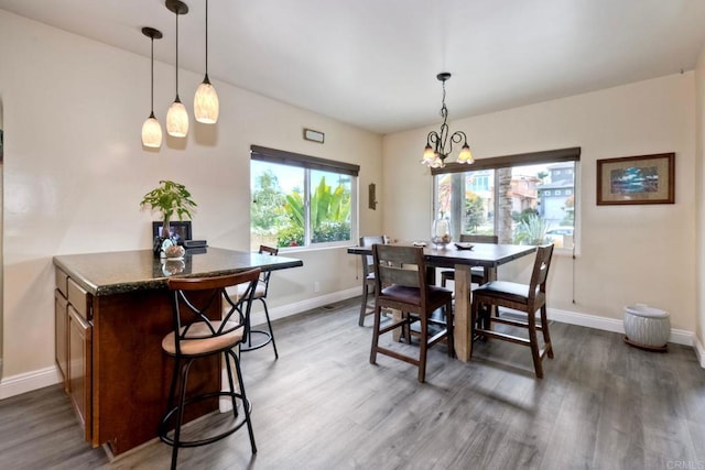 dining room featuring a chandelier, baseboards, and wood finished floors