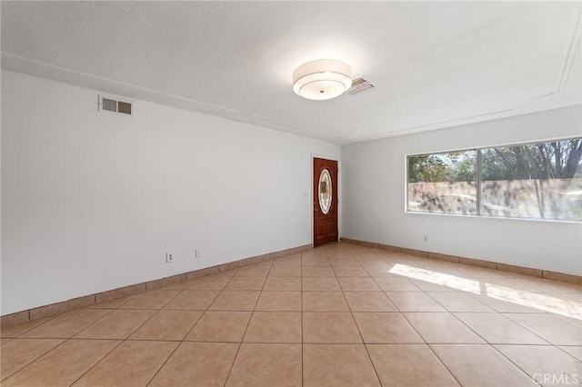 empty room with light tile patterned flooring, visible vents, and baseboards