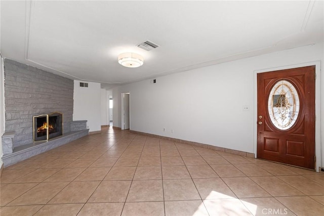 unfurnished living room with light tile patterned floors, baseboards, visible vents, and a large fireplace