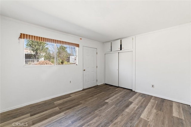 unfurnished bedroom with a closet, baseboards, and wood finished floors