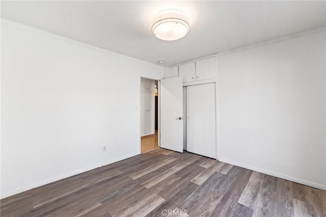 spare room featuring wood finished floors, baseboards, and ornamental molding