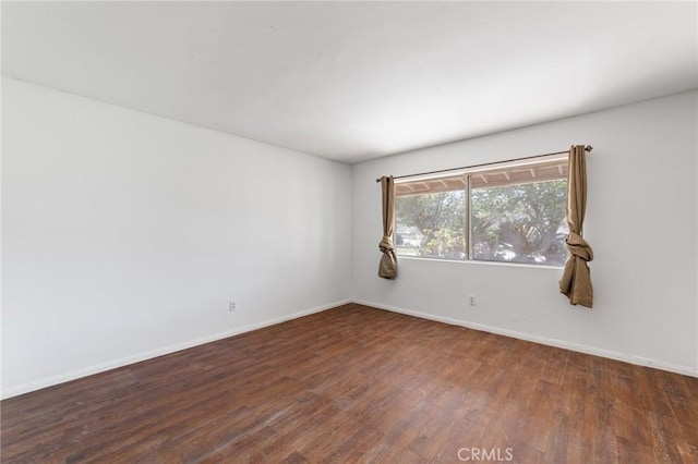 spare room featuring baseboards and wood finished floors