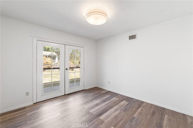 spare room featuring visible vents, baseboards, ornamental molding, french doors, and wood finished floors