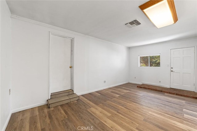 spare room with visible vents, baseboards, wood finished floors, and crown molding