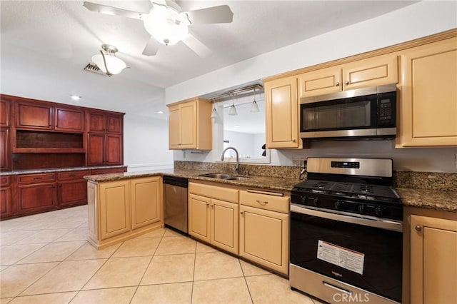 kitchen with dark stone counters, light tile patterned flooring, ceiling fan, a sink, and appliances with stainless steel finishes