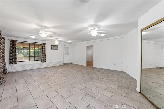 unfurnished living room featuring brick wall, ceiling fan, an AC wall unit, light tile patterned floors, and a textured ceiling