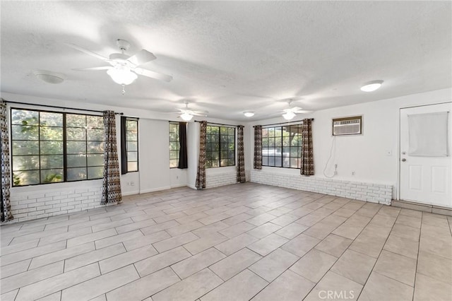 unfurnished room with a textured ceiling, brick wall, a ceiling fan, and a wall mounted AC