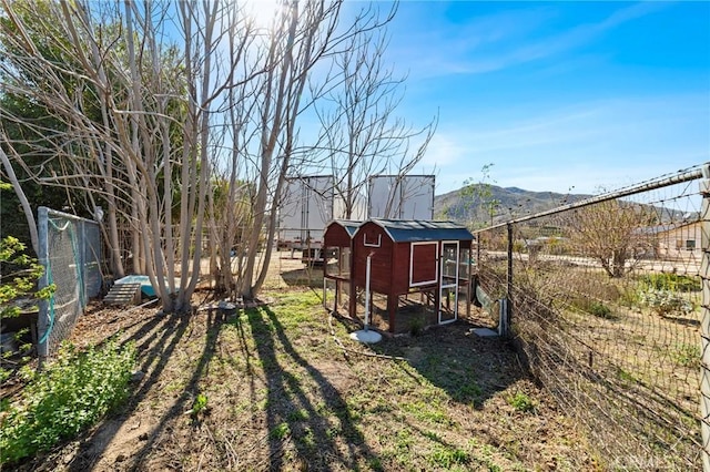 view of yard with an outbuilding, a mountain view, exterior structure, and fence