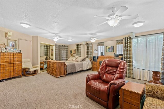 carpeted bedroom with a closet, a textured ceiling, and a ceiling fan