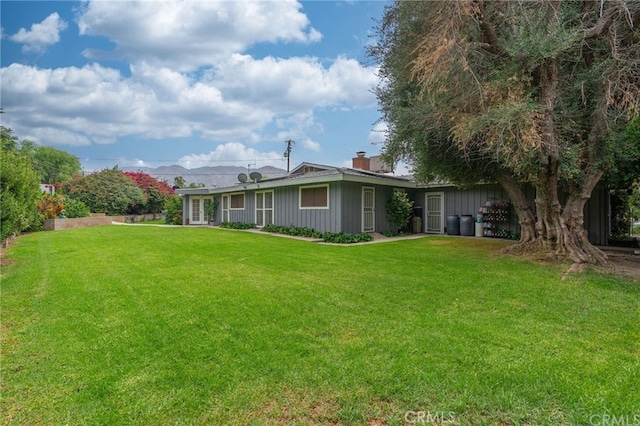 rear view of property featuring a lawn and a chimney