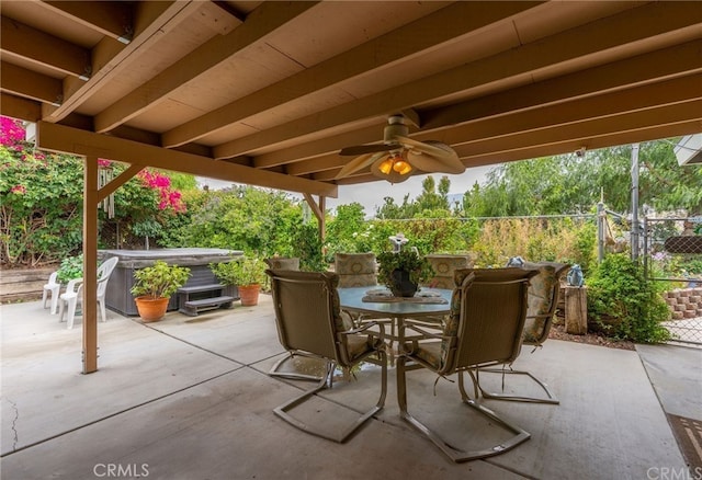 view of patio / terrace featuring fence, outdoor dining space, a ceiling fan, and a hot tub