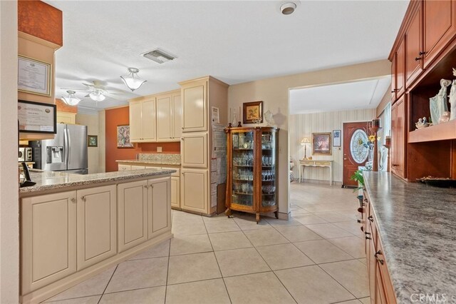 kitchen with visible vents, cream cabinetry, a ceiling fan, stainless steel fridge, and light tile patterned floors