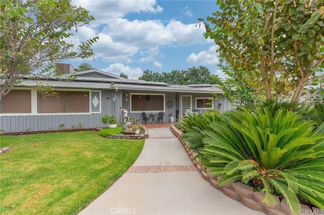 ranch-style home featuring roof mounted solar panels, a porch, and a front yard