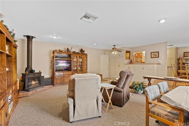 living area featuring visible vents, light carpet, recessed lighting, a wood stove, and a ceiling fan