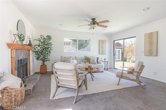 living area with a fireplace with raised hearth, recessed lighting, carpet floors, a ceiling fan, and baseboards