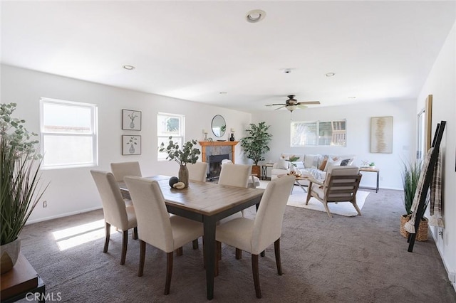 dining area featuring a ceiling fan, carpet, a fireplace, and baseboards