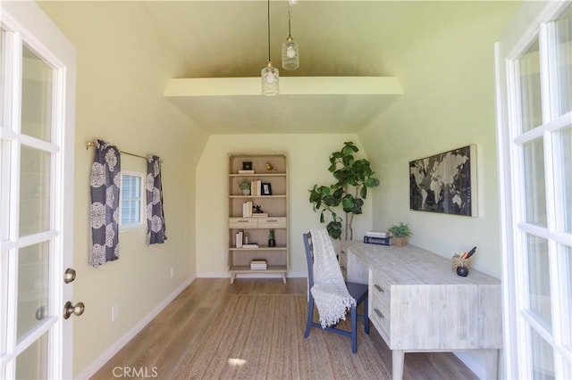 office featuring lofted ceiling, baseboards, wood finished floors, and built in study area